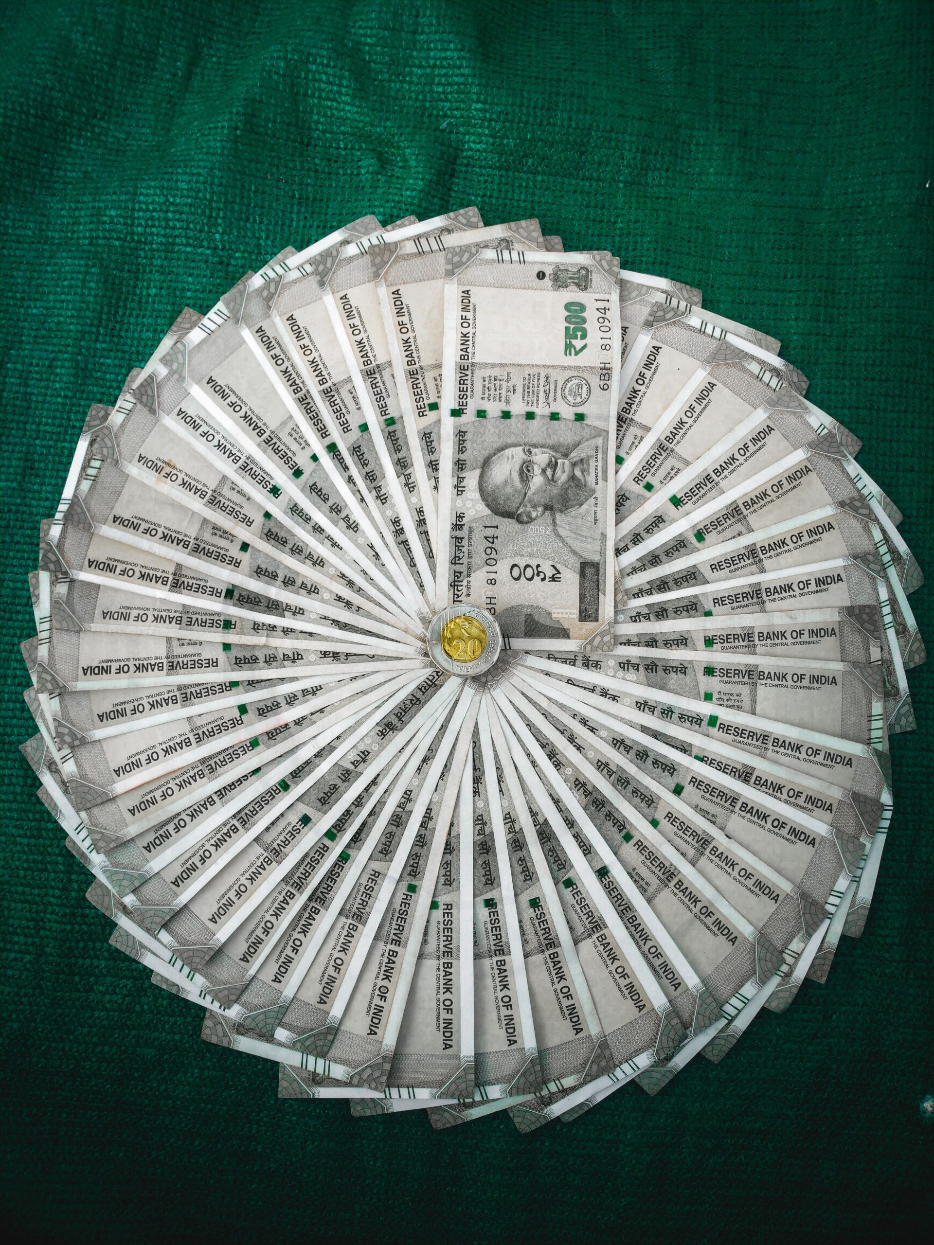 Top view of Indian Rupee notes arranged in a circular pattern on a green surface.